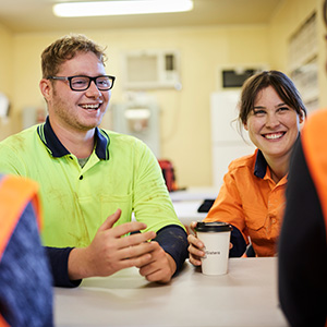 Male and female construction workers talking and smiling in tea room
