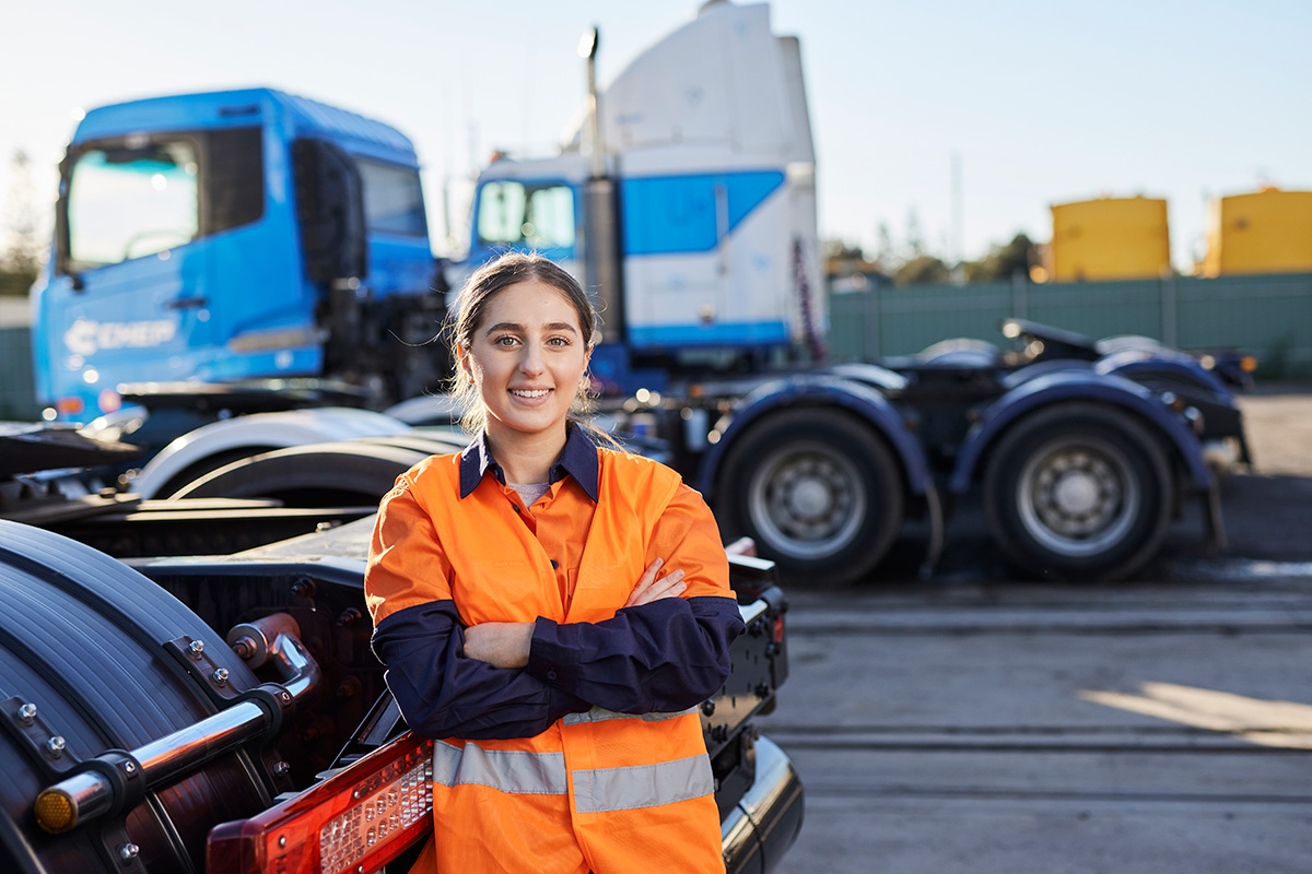 Female truck driver standing in front of trucks
