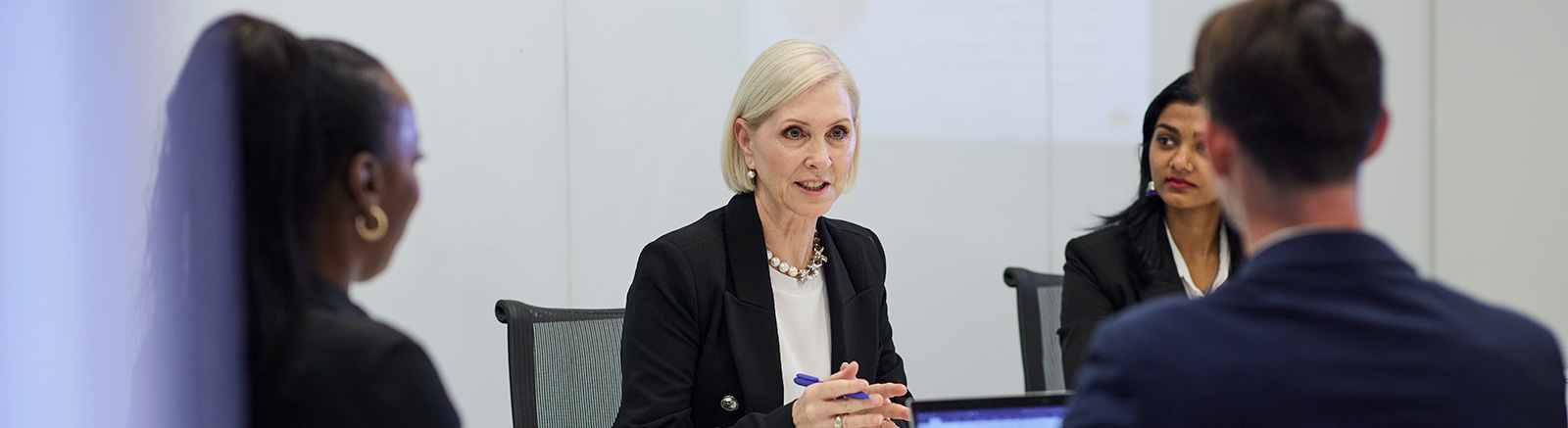 A woman with headphones is looking at a computer screen.